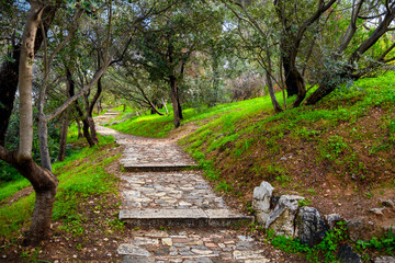 The shaded stone walking path and trail up Philopappos Hill towards the monument in the historic...