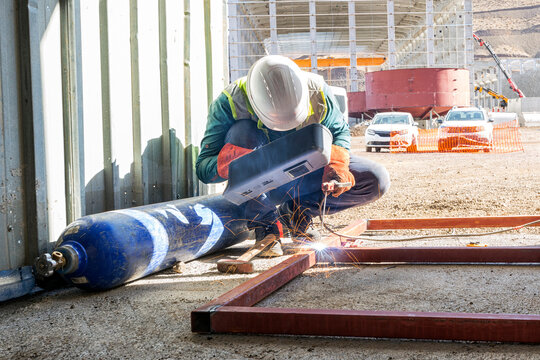 Welder is welding to steel material near to oxygen cylinder in the construction site. A gas cylinder is a pressure vessel for storage and containment of gases at above atmospheric pressure.