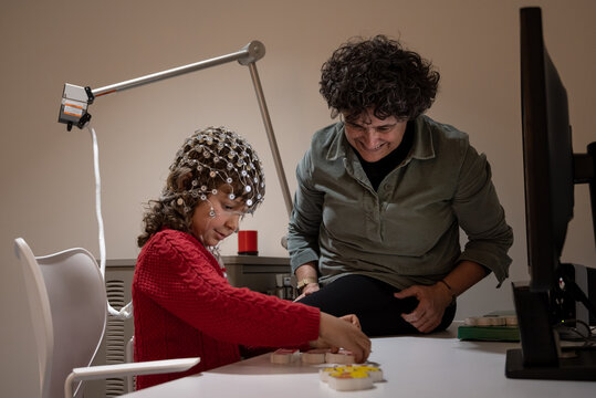 Researcher making neural study on kid in EEG cap