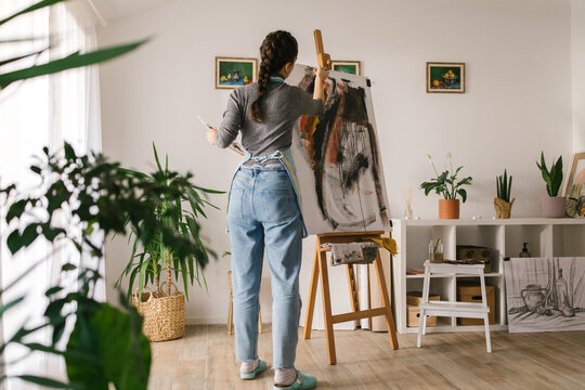 Female artist in art studio painting on canvas
