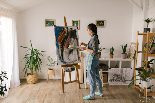 Female artist painting on canvas in home studio