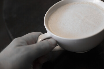 cup of latte in hand in the early morning at a coffee shop