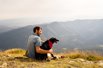 Portrait of happy man with his dog in nature at sunset