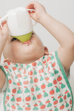 Baby With A BIb Drinking From A Sippy Cup