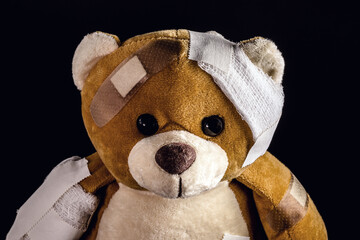 closeup of teddy bear bandaged with bandages and band aid, concept of child abuse or violence,...