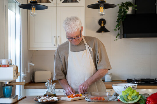 Senior man cooking preparing healhty meal in kitchen