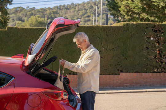 Senior Man Picking The Weekly Grocery Shopping From Car