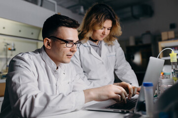 Scientist typing result of research on laptop