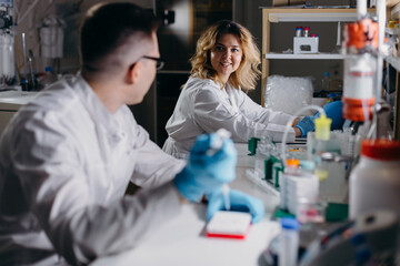 Biologist doing test and talking to colleague in lab