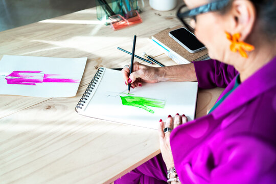 Mature fashion designer drawing designs on paper
