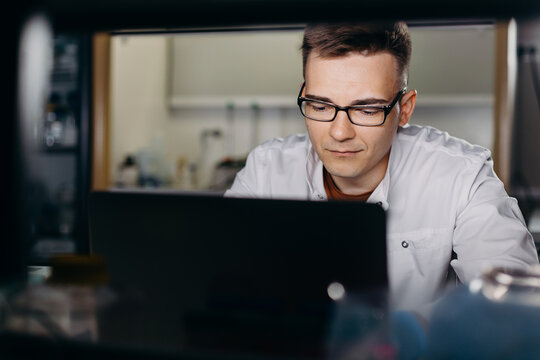 Busy man working on laptop in biochemical laboratory