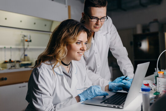 Smiling woman using laptop with colleague in lab