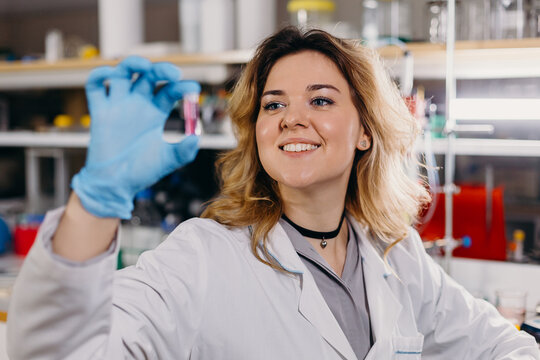 Smiling woman checking test tube with liquid sample