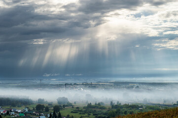 God Rays and Fog Above small Industrial Town after Rain
