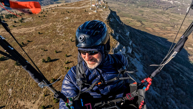 portrait of paraglider pilot mid-flight 