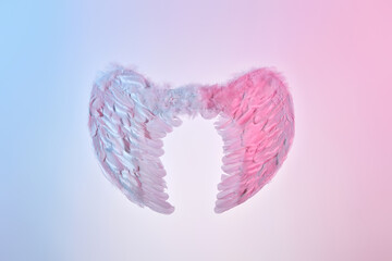 White angel wings of feathers over gradient background