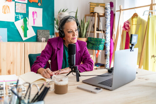 Senior woman in workplace making zoom on laptop