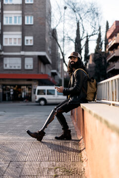 Trendy man with artificial limb using phone on street