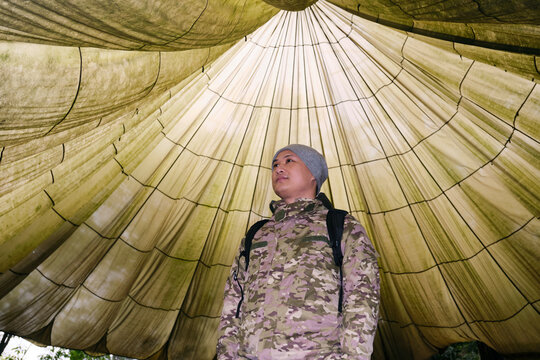 Asian man under large parachute outdoors

