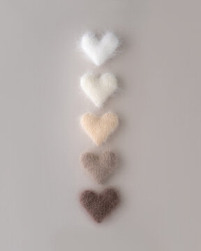 Fuzzy knitted hearts arranged in line on grey background
