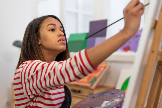 Woman painting on easel in workshop