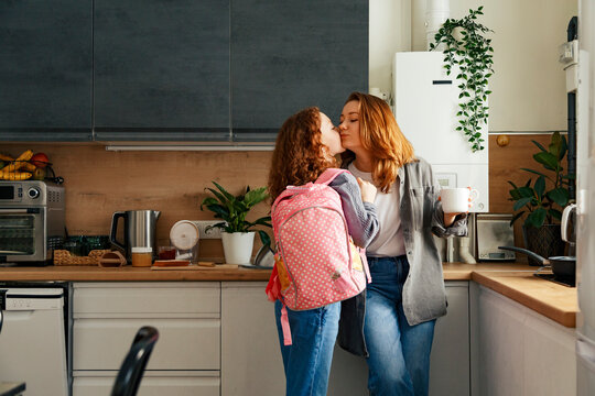 Daughter kissing mother before going to school - Powered by Adobe