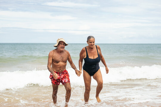 Elderly couple coming out of the sea laughing