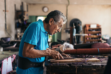Hispanic senior shoemaker working in his workshop