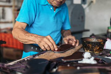 Senior shoemaker dyeing some soles