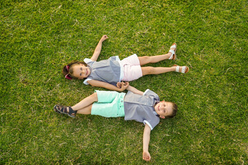 Niños Hermanos amigos jugando acostados en el jardín disfrutando felices en el parque en el...