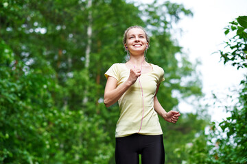 Running woman atletic spotsman trains in the summer park. Outdoor fitness portrait after rain