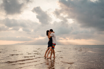 Happy hugged couple kissing on the shore