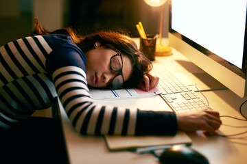 When you just cant keep your eyes open any longer. Shot of a young businesswoman sleeping on her desk while working late in an office. - obrazy, fototapety, plakaty