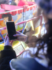 Woman using the mobile in front of a night fair