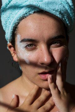 Woman in towel with white mask on face closeup portrait.