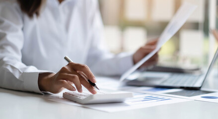 Close up Business woman using calculator and laptop for do math finance on wooden desk in office...