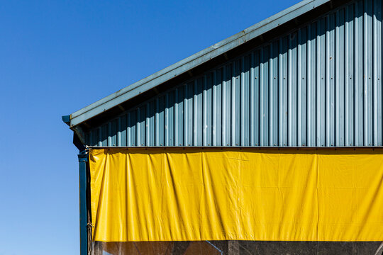 Yellow tarp hanging from a triangular aluminum wall 