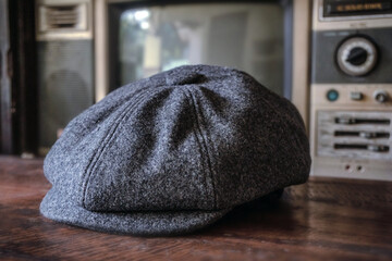 Detail of a classic eight-panel newsboy hat in tweed fabric herringbone in midnight black on a classic electronic background - obrazy, fototapety, plakaty