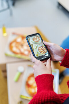 Woman taking picture of pizza on smartphone