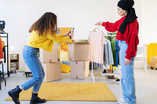 Diverse women taking picture of clothes in new flat