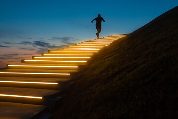 a man runs up a glowing staircase after sunset