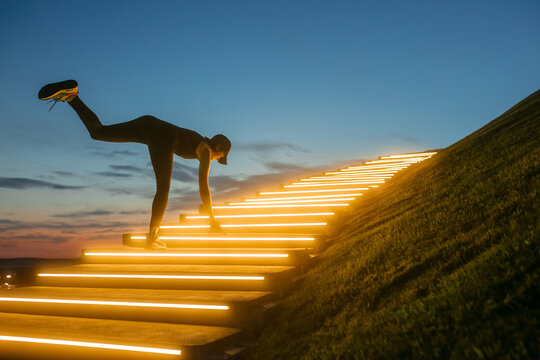 A woman kneads her body on the steps with illumination