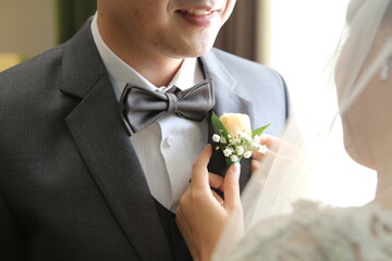 the bride helps put the corsage on the groom