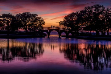 Selbstklebende Fototapeten Hochrot People on a bridge watching a sunset  © Zach