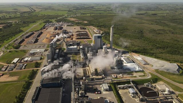 Smoking chimneys in paper mill factory and surrounding landscape, Fray Bentos in Uruguay. Aerial panoramic view