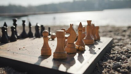Antique chessboard on sand beach by the water, slow motion artistic shot