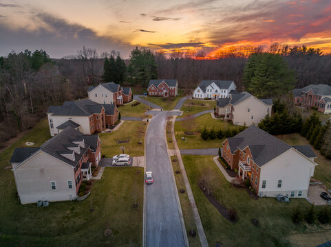 Colorful orange evening sun is setting over upper class East Coast American neighborhood cul-de-sac dead end street
 with large single family homes with big real estate lots and brick front