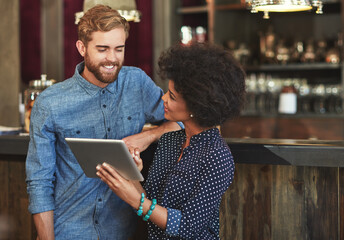 Adding new items to their online menu. Shot of a young man and woman using a digital tablet together at a cafe.