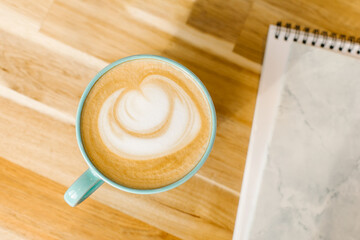 Cappuccino coffee in blue cup on wooden table in cafe. Top view
