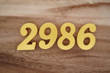 Golden Arabic numerals on a real brown and white wooden floor number 2986